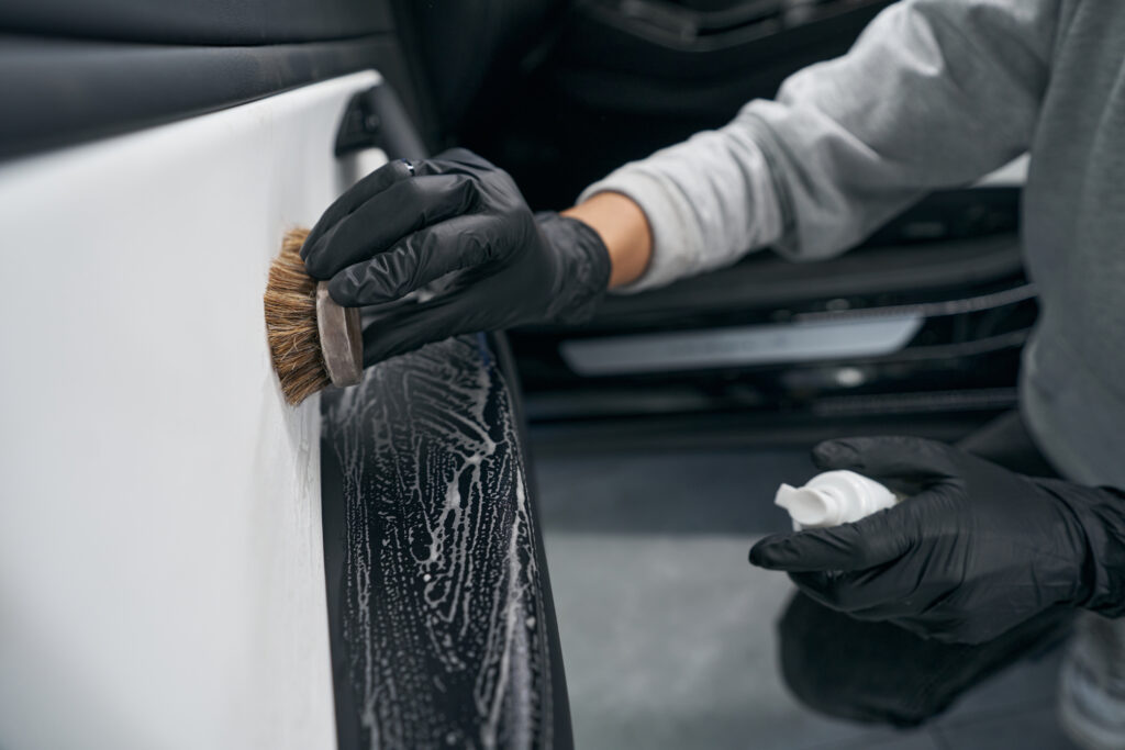 Photo recadrée d'un détaillant automobile lavant la surface intérieure du panneau de porte de voiture